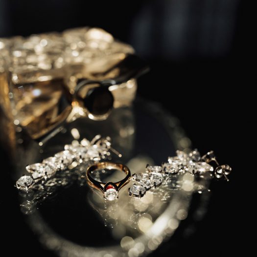 Wedding photo details. Perfume and elegant silver earrings and wedding ring of the bride on a glass table. Beautiful light. Reflection Luxury accessories